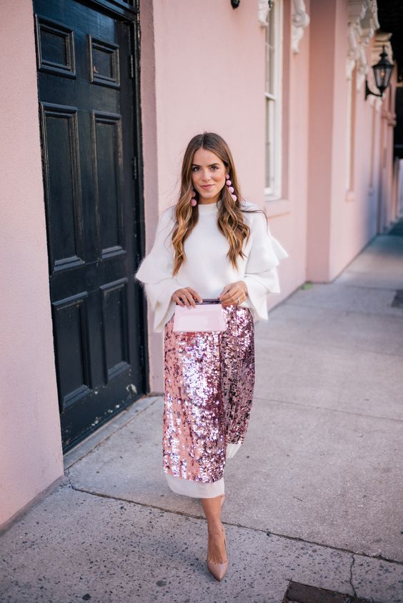 a pink sequin midi skirt with a white edge, a white angora sweater with ruffled sleeves, pink earrings and nude heels