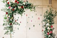 18 a red and green wedding arch with greenery, blooms and hanging agates for a trendy feel