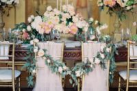 18 blush tulle covering the chairs in layers and a greenery and bloom garland to tie the sweetheart chairs and make them stand out