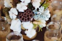 a rustic centerpiece with pale miller, wheat, cotton and greenery for a fall or winter wedding