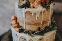 21 a naked wedding cake with dripping, evergreens, privet berries and topped with donuts