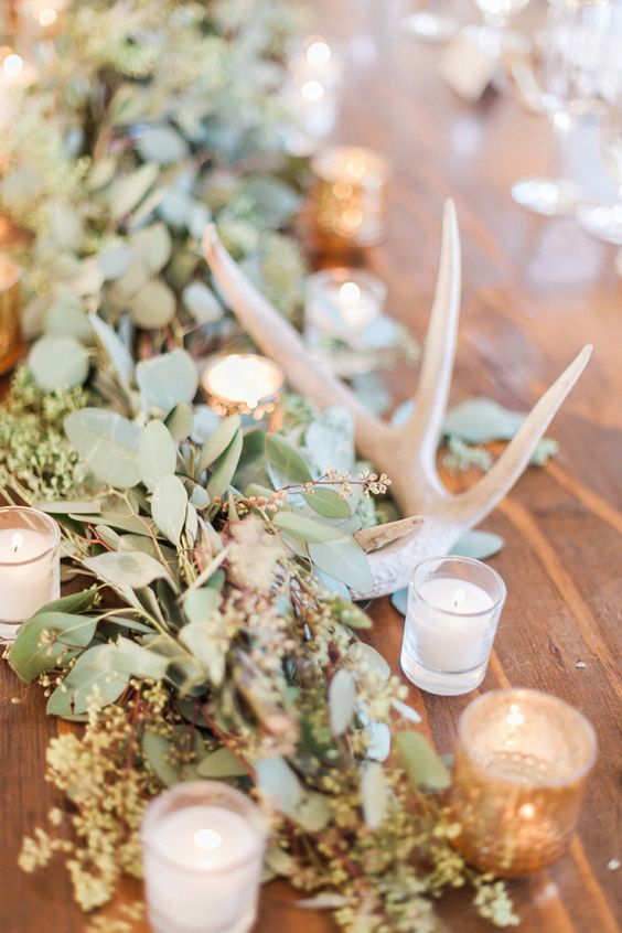 wedding table decor with lush greenery, candles and antlers is a great idea for a rustic wedding