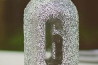 22 a silver glitter mason jar with a table number doubles as a candle lantern