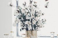23 a gilded vase with cotton branches is a chic idea to add coziness to your winter wedding
