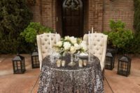 23 a glam sweetheart table with white upholstered chairs, a silver sequin tablecloth, white blooms and candles