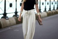 24 a black shirt with embellished sleeves, neutral flowy pants, a statement necklace, black suede shoes and a leopard print clutch