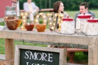 25 a gorgeous s’mores bar made of a wooden table, with a chalkboard sign and marquee letters