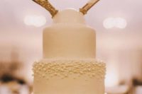 25 a neutral yet textural wedding cake with a gilded antler topper for a woodland wedding