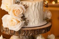 26 a rustic frosted wedding cake with creamy roses and an antler cake topper