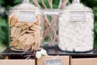 26 an s’mores station for a farm wedding arranged with sticks, large jars and drawers for storing everything necessary