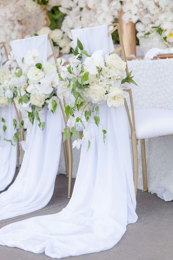 pure white chair covers with lush white flowers and foliage for a lush spring or summer wedding