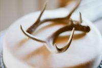 27 a neutral wedding cake with a simple antler topper looks chic and rustic
