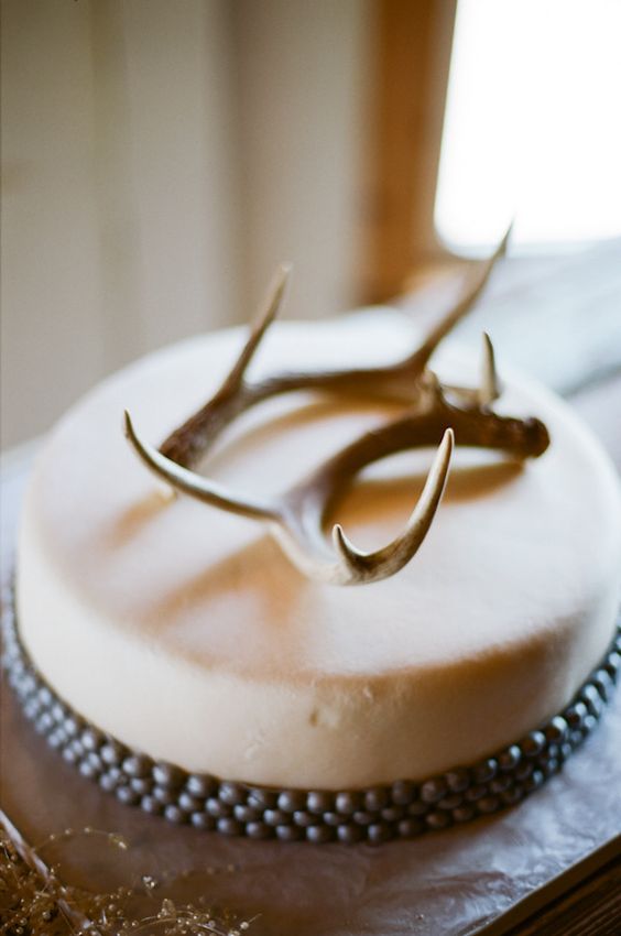 a neutral wedding cake with a simple antler topper looks chic and rustic