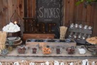 27 a rustic s’mores bar with a burlap banner, sticks, glass bowls and marquee letters