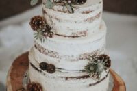 27 a semi-naked wedding cake with foliage, thistles and pinecones and wood slice toppers