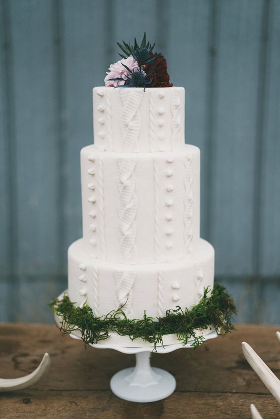 a cable knit wedding cake with moss and topped with thistles, a lavender rose and a burgundy one