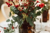 a beautiful Christmas wedding centerpiece of an apothecary bottle, greenery, berries looks very festive and cozy