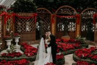 a beautiful Christmas wedding ceremony space in a botanical garden, with lots of red poinsettias blooming