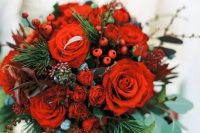 a bold Christmas wedding bouquet of red blooms, berries, greenery and fir branches is bright