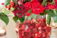 a bold winter centerpiece of a vase filled with cranberries, red blooms, leaves and berries is a perfect winter or Christmas wedding decoration you may easily make