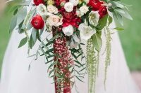 a cascading Christmas wedding bouquet of red and white blooms, foliage and berries and bright ribbons