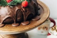 a chocolate wreath wedding cake with chocolate drip, evergreens and raspberries for Christmas