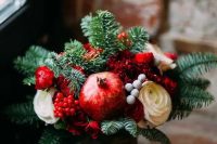 a cozy winter wedding bouquet of fir, red and white blooms, berries and pomegranates for a winter or Christmas wedding