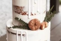 a delicious-looking naked two-tier wedding cake with creamy drip, crusty donuts and greenery is a very chic and lovely idea