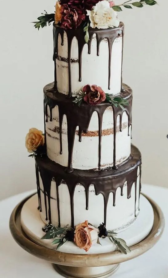 a fantastic three-tier naked wedding cake with chocolate drip, blooms, greenery is a gorgeous idea for many weddings