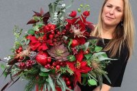 a fantastic wedding centerpiece of a red bucket, greenery and evergreens, red berries, pomegranates, poinsettias and LEDs