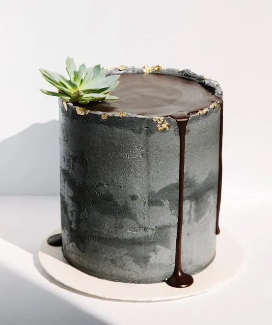 a grey concrete wedding cake with chocolate on top and some chocolate drip, a succulent for a modern wedding