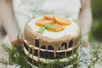 a naked wedding cake with caramel dripping, ferns and citrus slices