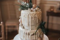 a naked wedding cake with creamy drip, white chocolate, greenery on top for a neutral winter wedding