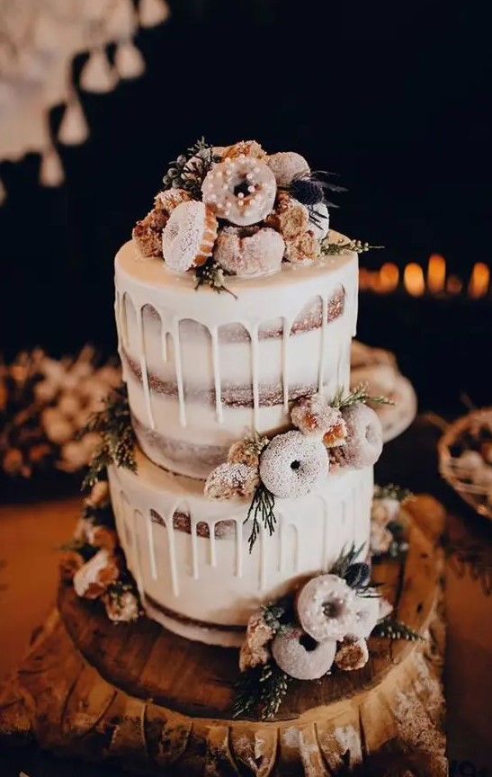 a naked wedding cake with creamy drip, with wildflowers, thistles and glazed donuts for a winter rustic wedding