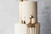 a neutral winter wedding cake with gold drip, macarons, gilded cherries, willow is amazing