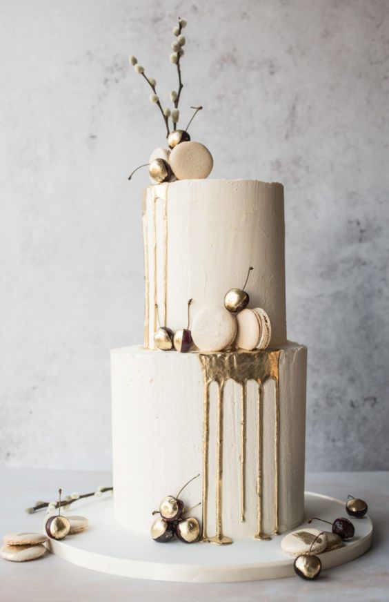 a neutral winter wedding cake with gold drip, macarons, gilded cherries, willow is amazing
