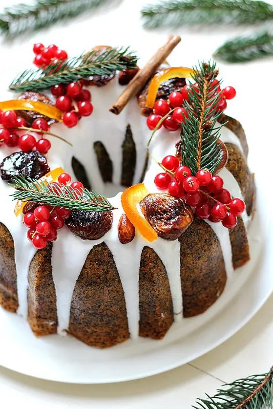 a poppy seed bundt wedding cake with white chocolate drip, cranberries, evergrenes, cinnamon and candied fruit