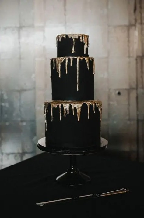 a refined and contrasting matte black wedding cake with gold dripping is a stylish modern idea, suitable for a Halloween or NYE wedding, too