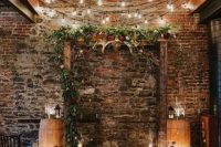 a stained wood Christmas arch decorated with greenery, evergreens, red blooms, antlers, pillar candles with lights over it