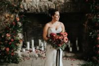 a stunning Christmas wedding backdrop – an old stone fireplace with pillar candles, greenery and red bloom arrangements is pure romance