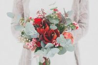a tender bouquet with red blooms, pomegranate, eucalyptus and dark foliage for a Christmas wedding
