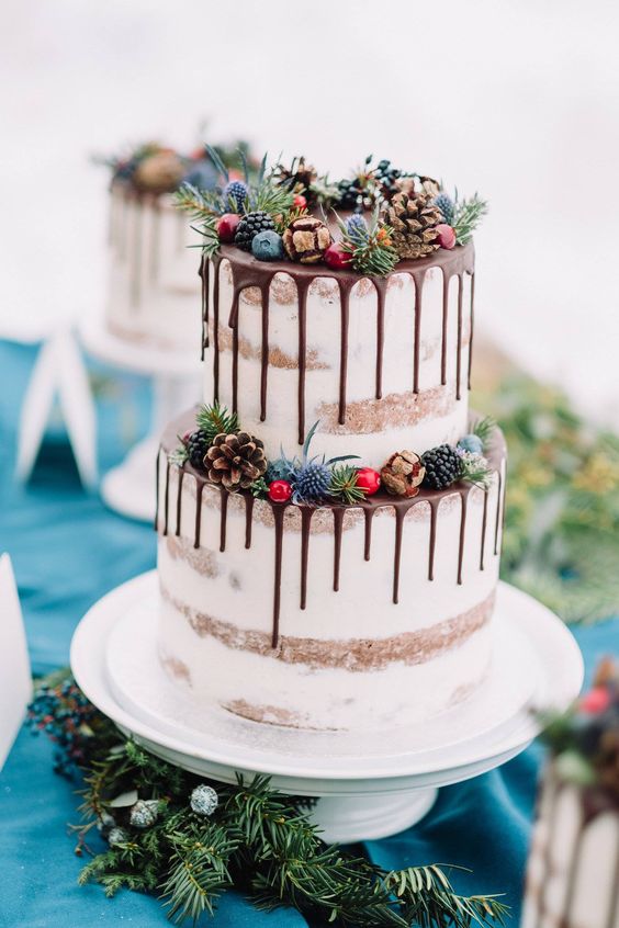 a winter drip wedding cake with chocolate drip, pinecones, thistles, berries is a very cool and eye-catching idea