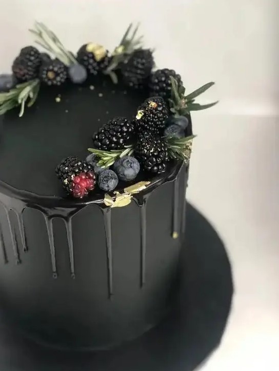 an elegant and moody plain black wedding cake with black drip, gold leaf, blackberries, blueberries and herbs on top is a chic and modern idea to rock