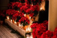 bold Christmas wedding decor with red poinsettias in planters and pillar candles plus evergreens are a lovely idea