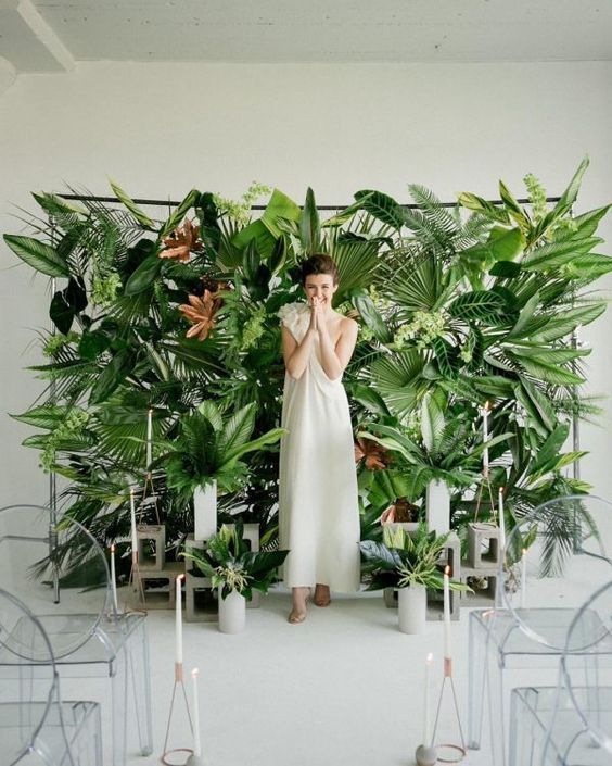 a lush tropical leaf wall and leaves in concrete vases create bold modern tropical decor