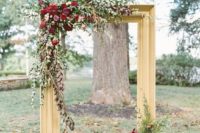 02 a refined backdrop with a large gilded frame, lush greenery and bold burgundy blooms plus candles around