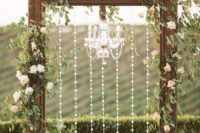 03 a gorgeous backdrop with a large vintage wooden frame decorated with crystals and a crystal chandelier, greenery and blush blooms