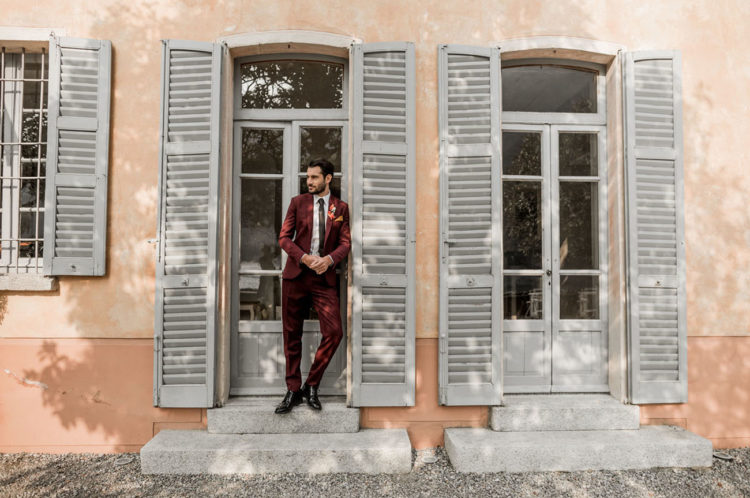 The groom was wearing a burgundy wedding suit and black shoes