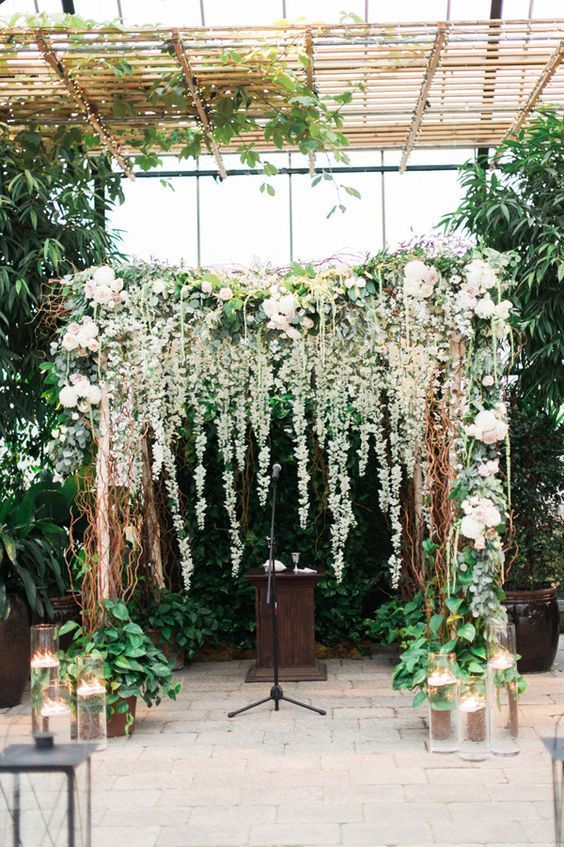 a gorgeous lush floral and greenery backdrop with an arch to feel like outdoors