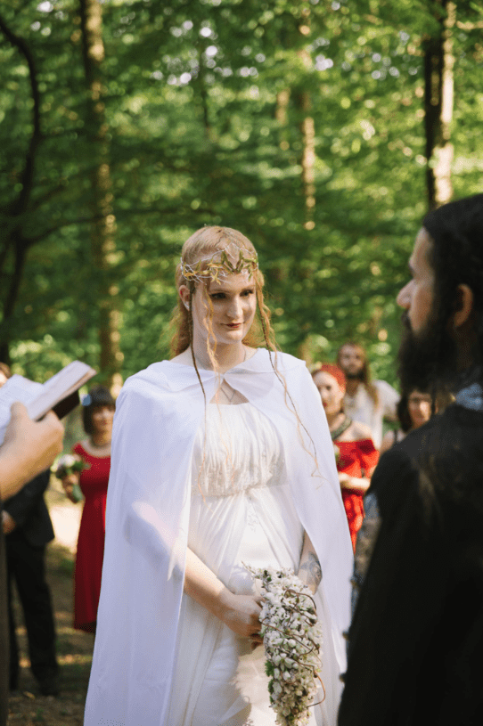 The bride was wearing a flowy light dress and a cap, a perfect elvish headpiece and a braided half updo